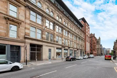 a street with cars parked in front of a building at Merchant City Apartment in Glasgow