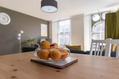 a glass bowl of oranges on a wooden table at Merchant City Apartment in Glasgow