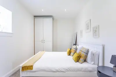 a white bedroom with a bed with yellow pillows at South Barlogan Farm in Bridge of Weir