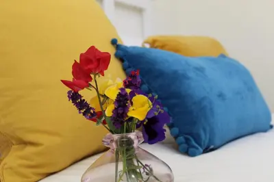 a vase filled with flowers on a table with pillows at South Barlogan Farm in Bridge of Weir