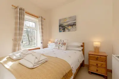 a bedroom with a bed and a window at Foxglove Cottage in Maybole