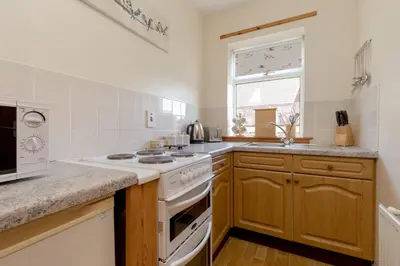 a kitchen with a white stove top oven next to a window at Foxglove Cottage in Maybole