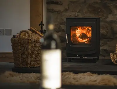 a bottle of wine sitting in front of a fireplace at Auchnabreac Cottage in Carradale