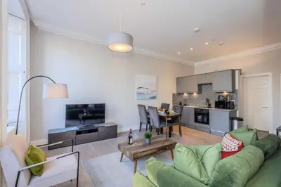 a living room with a green couch and a table at Dragon Suites - Edinburgh City Centre 2 Bed Apartment in Edinburgh