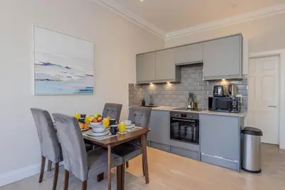 a kitchen with a wooden table with chairs and a tableasteryasteryasteryasteryastery at Dragon Suites - Edinburgh City Centre 2 Bed Apartment in Edinburgh