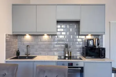 a kitchen with white cabinets and a sink and a microwave at Dragon Suites - Edinburgh City Centre 2 Bed Apartment in Edinburgh