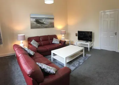 a living room with a couch and a table and a tv at The Station Apartment in Kilmarnock
