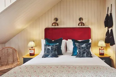 a bedroom with a bed with a red headboard and pillows at No.26 By The Sea in Oban