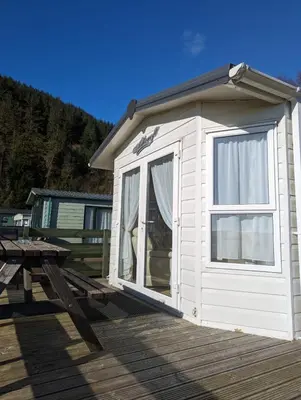 a small white cabin with a picnic table on a deck at The Ashcroft Sea View 6 in Dunoon
