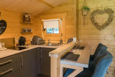 a kitchen in a log cabin with a wooden table at 1-Bed Cabin 2 adults Wood Burning Hot Tub & Fire in Carluke