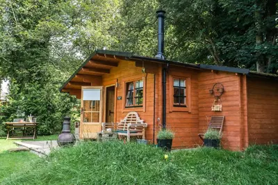 a small wooden cabin in the grass with a table at 1-Bed Cabin 2 adults Wood Burning Hot Tub & Fire in Carluke