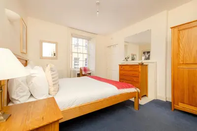 a bedroom with a bed and a wooden dresser at JOIVY Gorgeous 2-bed flat near Edinburgh Castle in Edinburgh