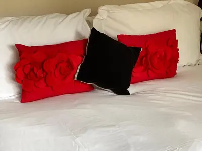 a bed with two red pillows and a pile of roses at Lochay Lodges in Killin
