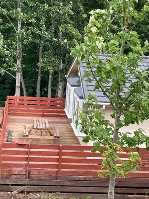 a large wooden deck with a bench and a tree at Lochay Lodges in Killin