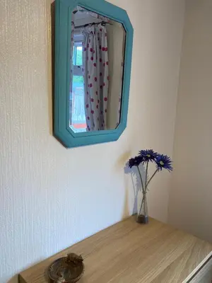 a mirror on a wall with a vase of flowers on a table at Lochay Lodges in Killin
