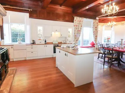 a kitchen with white cabinets and a dining room at Auchentroig House in Stirling