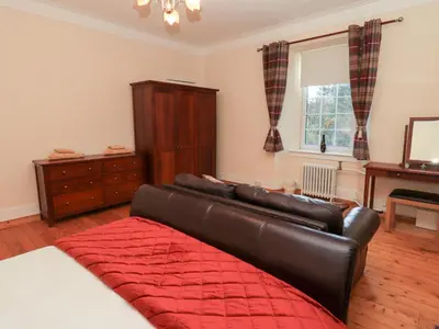 a living room with a leather couch and a window at Auchentroig House in Stirling