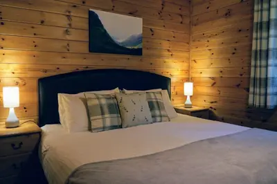 a bedroom with a bed with two lamps on tables at Woodland Spruce Lodge in Killin