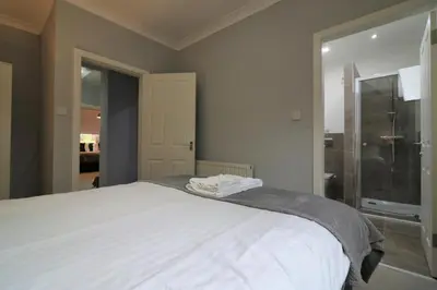 a bedroom with a large white bed and a shower at Signature - Moss View in Govan