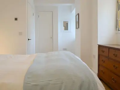 a white bedroom with a bed and a dresser at Printmakers Cottage in Bellanoch