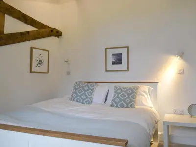 a bed with white sheets and pillows in a room at Printmakers Cottage in Bellanoch
