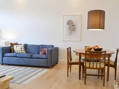 a living room with a blue couch and a table at Printmakers Cottage in Bellanoch