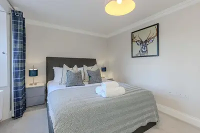 a bedroom with a bed with a white bedspread at Dragon Suites - Edinburgh City Centre 2 Bed Apartment in Edinburgh
