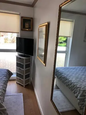 a mirror in a bedroom with a bed and a television at Limegrove Comfortable three bedroom house in Law