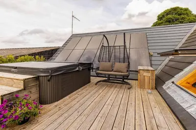a patio with a chair on a wooden deck at Luxury Duplex - Sleeps 2 - Hot Tub - Parking in Glenfarg