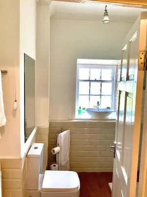 a bathroom with a sink and a toilet and a window at Old Spittal Hospital Apartment - Free Parking in Stirling