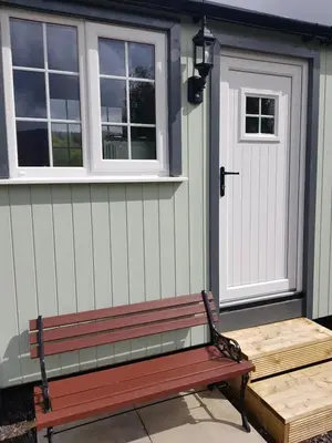 a bench sitting outside of a house with a door at Wee Highland Hideaway Hut in Dalmally