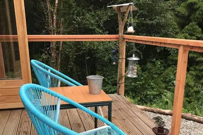 a table and two chairs on a deck with a cup on it at Off Grid 1-Bed Cabin Pets Ok 20 mins to Dunoon in Blairmore