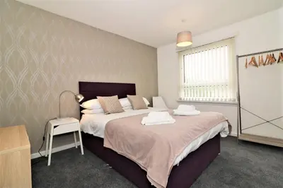 a bedroom with a bed and a table and a lamp at Signature - Troon View in East Kilbride
