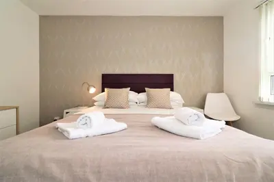 a bedroom with a large bed with two white towels at Signature - Troon View in East Kilbride
