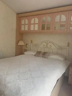 a bedroom with a white bed with a cabinet above it at Lyndhurst Corner 72 in Dunoon