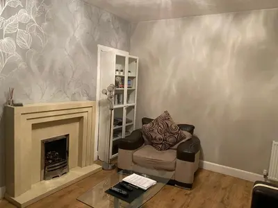 a living room with a chair and a fireplace at Nairoo in Balloch