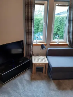 a living room with a blue couch and a table at Ardgowan Cottage in Brodick
