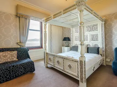 a bedroom with a canopy bed and a chair at The Old Nunnery - Uk7122 in Skelmorlie