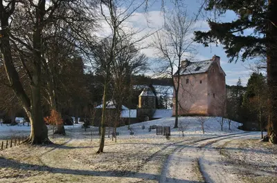 an old building in the snow with a bridge in the background at Barns Tower in Peebles