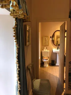 a bathroom with a toilet and a mirror and a curtain at Barns Library in Peebles