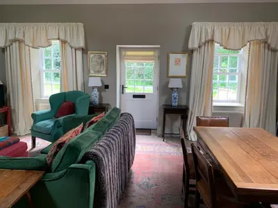 a living room with green chairs and a wooden table at Barns Library in Peebles