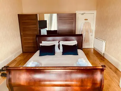 a bedroom with a large wooden bed with blue pillows at Ardmor Guest House in Oban