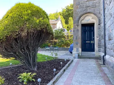 a house with a blue door and a tree at Ardmor Guest House in Oban