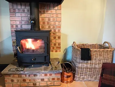 a stove in a living room with a brick fireplace at The Bothy Claymires Loch Lomond & Stirling in Buchlyvie