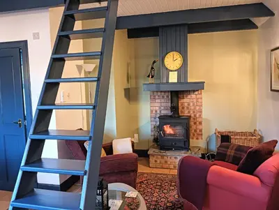 a living room with a ladder and a fireplace at The Bothy Claymires Loch Lomond & Stirling in Buchlyvie