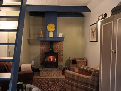 a living room with a brick fireplace with a clock at The Bothy Claymires Loch Lomond & Stirling in Buchlyvie