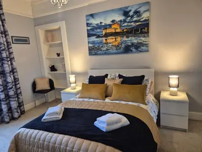 a bedroom with a large bed with two towels on it at Brae View Coastal Gem in Largs