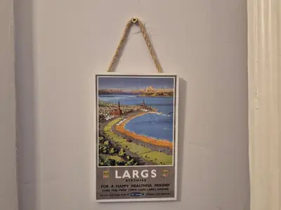 a sign hanging on a wall with a beach at Brae View Coastal Gem in Largs
