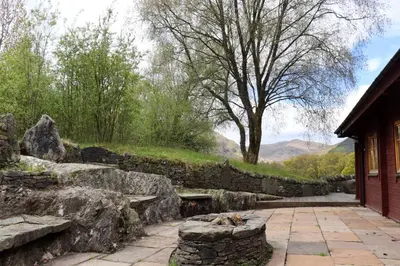 a stone wall next to a patio with a dog laying on a bench at Lodge 38 Rowardennan , Loch Lomond in Glasgow