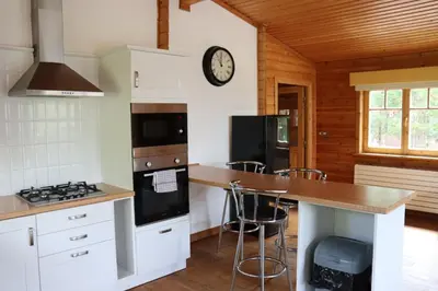 a kitchen with white cabinets and a counter with stools at Lodge 37 Rowardennan, Loch Lomond in Glasgow